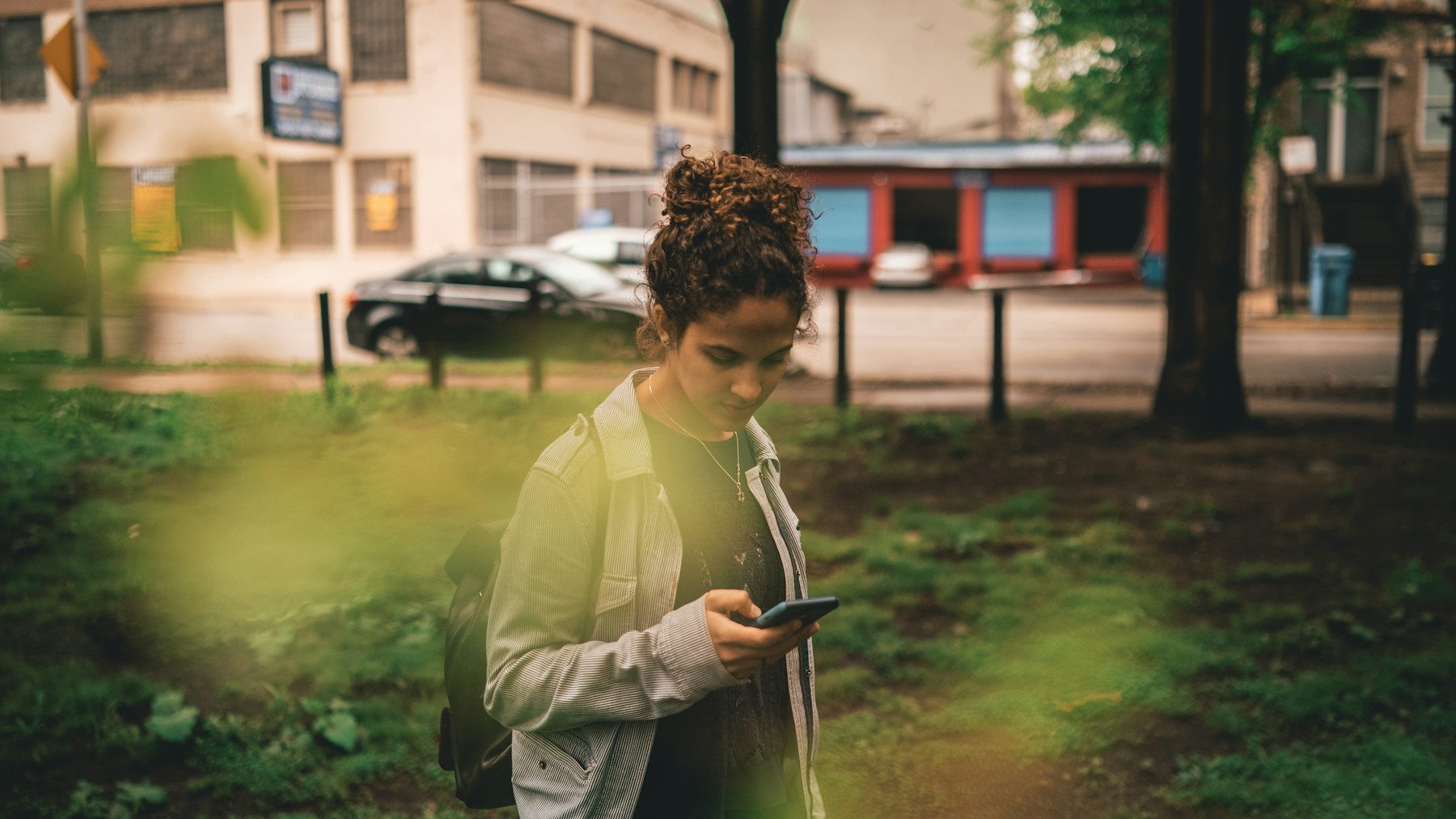 a woman standing in the grass looking at her cell phone